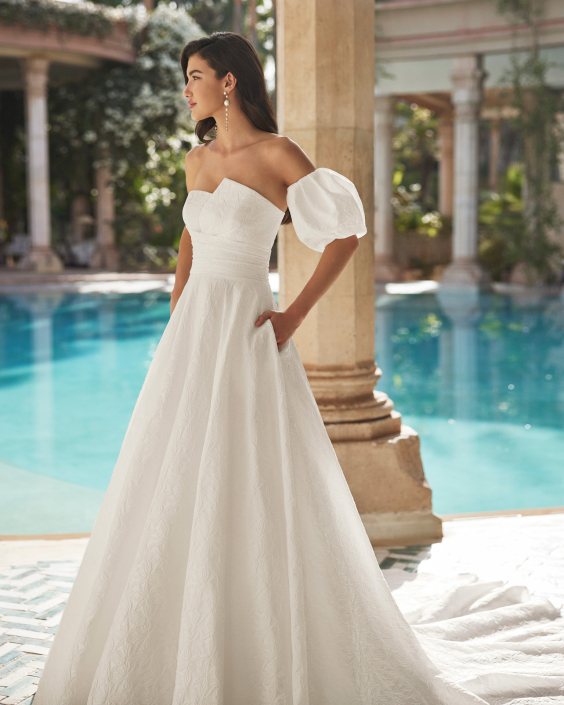 Azaly – From £1310 Azaly – From £1310 With or without puff sleeves. Available in Brocade, Satin, and Nature Brocade.
