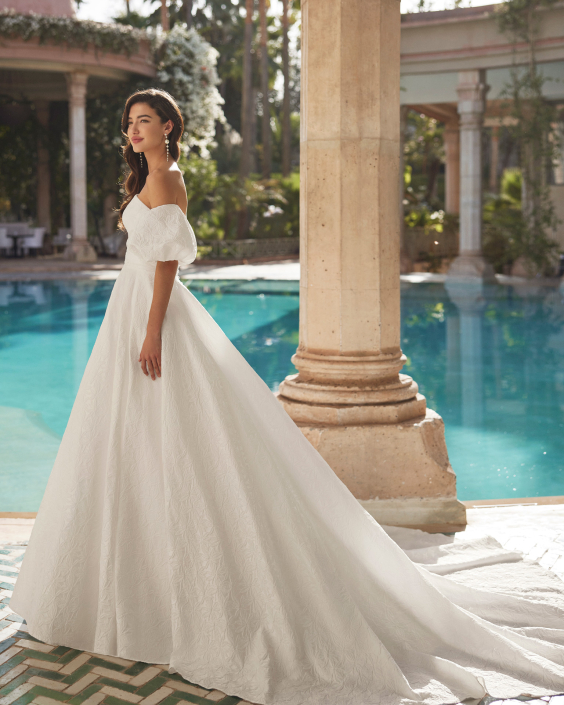 Azaly – From £1310 Azaly – From £1310 With or without puff sleeves. Available in Brocade, Satin, and Nature Brocade.